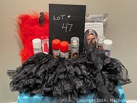 Assortment of Halloween dress up items including black tutu skirt, orange fuzzy leg warmers, multiple spray cans, and a packaged adult wig shown with lot number board.