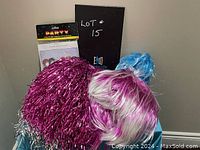 Photo showing pile of novelty wigs including magenta tinsel, blue polyester and magenta/white polyester wigs.