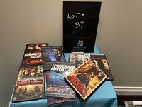 Photo showing lot #37 with 8 DVD movie cases arranged on a blue tablecloth. Visible titles include Planet of the Apes, Kong, The Illusionist, and more.