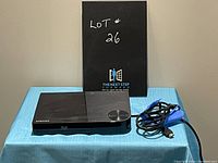 Front and top view of black Samsung Blu-ray DVD player with accompanying power cable.