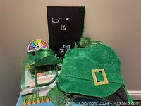Photo of St. Patrick's Day themed hats, headbands, and beaded necklaces showing multiple green festive items including a large velvet leprechaun hat with a gold buckle.