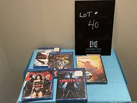 Lot of 6 superhero DVDs and Blu-rays displayed on a blue surface with a sign showing lot number 40.