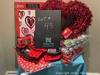 Image of assorted Valentine's Day party supplies and decorations including heart-shaped wreath, table covers, plates, napkins, glasses, and silicone molds.