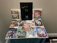 Photo showing 11 unopened Wii game cases arranged on a table, titles visible including Wii Sports, Just Dance series, Wii Fit, and others.