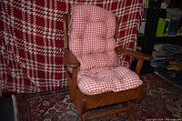 Front view of child's wooden rocking chair with red and white check cushioned seat and backrest.