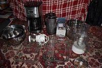 Photo showing Cuisinart coffee maker, stainless mixing bowls, Pyrex baking dishes, stainless colander, electric chopper, insulated thermos, and food processor attachment box.