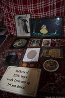 All 11 vintage wall decor pieces displayed on patterned fabric including framed prints, mirror, plaques, and sayings.