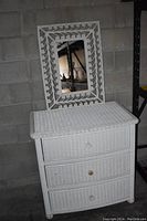 White wicker dresser with three drawers and round knobs. Visible wear and dirt marks.