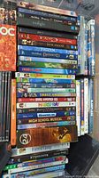 DVD spines stacked showing a variety of movies and TV series including Disney titles and popular movies.