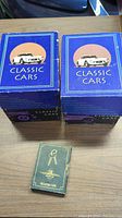 Two blue boxes labeled 'Classic Cars' alongside a small green collector cards box on a wooden surface.