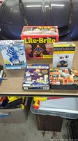 Photo of five boxed kids toys laid on a table showing Lite-Brite, Tech-Kit 3-in-1 Solarbot, KidzRobotix, ScienceWiz Inventions, and an additional toy box