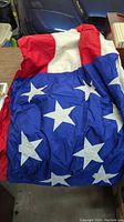 Photo of a large American flag, showing red and white stripes and a blue area with white stars