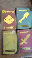The 4 Minecraft handbooks displayed with their front covers visible; all are hardcover with pixel art illustrations and titles.