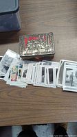 Photo showing the entire tin box and spread out vintage photographs on a table.