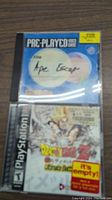 Two PlayStation game cases on a wooden surface, Ape Escape disc visible, Dragon Ball Z case marked empty.