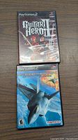 Top view of two PlayStation 2 game cases: Guitar Hero and Ace Combat 04 showing cover art.