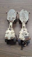Top view of both vintage roller skates showing white paint, rust spots, and wheels.