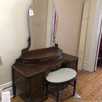 Front view of vanity table with mirror attached and stool positioned in front