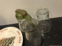 Three glass jars shown, one with green plastic lid and handle and two plain clear glass jars