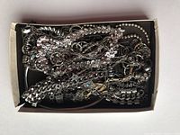 Box containing a large assortment of chunky silver-tone metal chain necklaces and bracelets, showing wear and mixed textures.