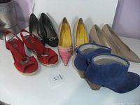 Shows entire lot of 6 pairs of women's dress shoes in various styles and colors arranged on a white surface.