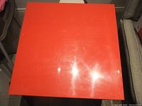 Top view of a red IKEA Malm end table showing the square red tabletop with surface scratches and wear.