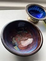 Round dark iridescent pottery bowl with multicolor glaze