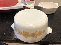 Vintage white Pyrex casserole dish with yellow flower design on the counter