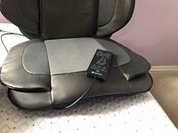 Side view of black and grey Confier massage seat cushion with attached wired remote on seat portion.