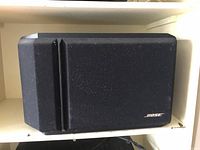 Close-up of one Bose black rectangular speaker with fabric front and Bose logo