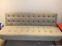 Front view of the grey tufted sofa bed in upright position