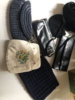 Multiple vintage evening bags including beaded, embroidered, leather and knit textures laid flat on surface.