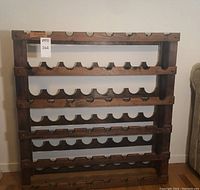 Front view of dark stained wooden wine rack with five shelves and semi-circular cutouts for bottle storage.