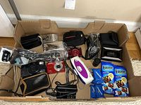 Overview of box containing film and digital cameras, cassette player and accessories