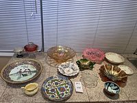 Overall view of various decorative plates and art glass bowls arranged together on a countertop.