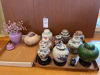 Full lot of 11 ginger jars and urns of varying sizes and materials arranged on a tray.