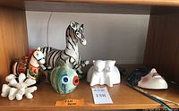 Shelf view showing all six decorative figures arranged including zebra, unicorn, fish, cat coin bank, coral, and mask.