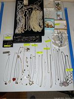 Overview of pearl strands on tray, gold chains, orphan earrings, pendant and magnetic necklace