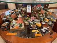 Overview of glass shelf display with assorted porcelain boxes and figurines, non-Limoges items on left and Limoges items on right.
