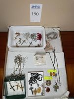 All religious jewelry lot items displayed on padded surfaces and trays including necklaces, wristband, and brooch