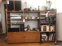 Front view of shelving unit filled with various items, speakers, books, and collectibles to demonstrate size and layout