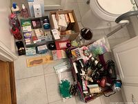 Wide shot of assortment on bathroom floor showing soaps, lotions, hair tools