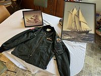 Overview showing jacket laid flat with two framed prints behind it