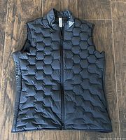 Front view of black ADIDAS women's goose down vest, showing full front zipper, waffle pattern, and Adidas logo near collar.