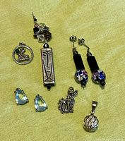 View of the assorted costume jewelry lot showing earrings, pendants and charms arranged on fabric.