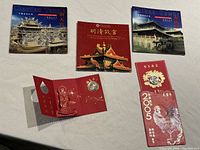 Five Chinese commemorative coins with associated booklets and folders displaying temples and historic buildings.