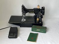 Singer machine on base with foot pedal, manual and attachments box in front