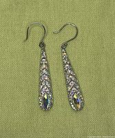 Front view of two sterling silver dangle earrings showing textured and reflective detail design on teardrop pendants and hook ear wires.
