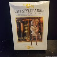 Front view of the original box with clear plastic window showing the City Style Barbie doll dressed in beige European-style couture outfit with handbag.