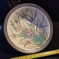 Top view of the porcelain bowl showing painted floral design with pink and white flowers and green leaves. Blue and gold Greek key pattern on rim.